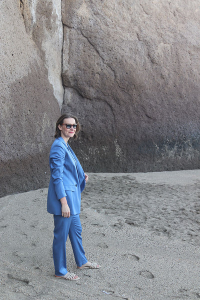 Frau in Kornblauem Anzug am Strand stehend